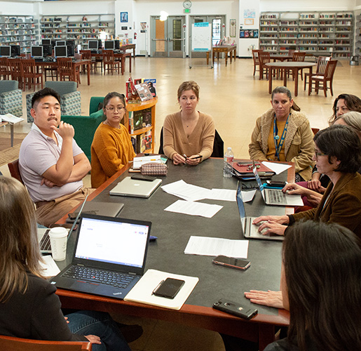 a group on people talking at a conference table in a library
