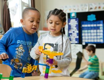 Two elementary students working together on a learning toy.