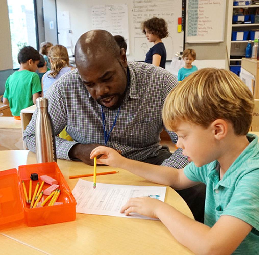 Teacher and elementary aged students working at a table