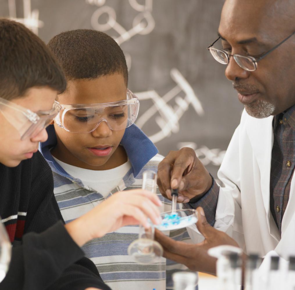 science teacher working on a project with two elementary aged students