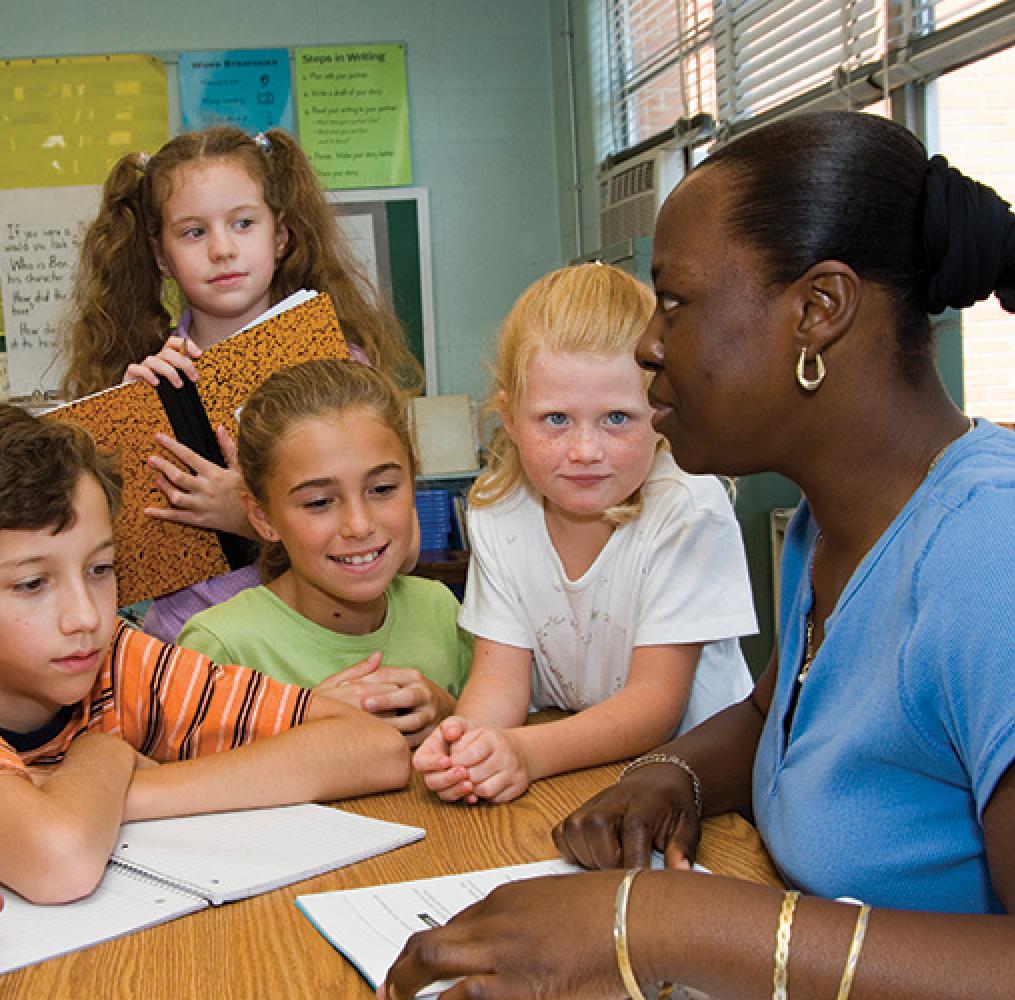 Teacher working at a table with elementary aged students