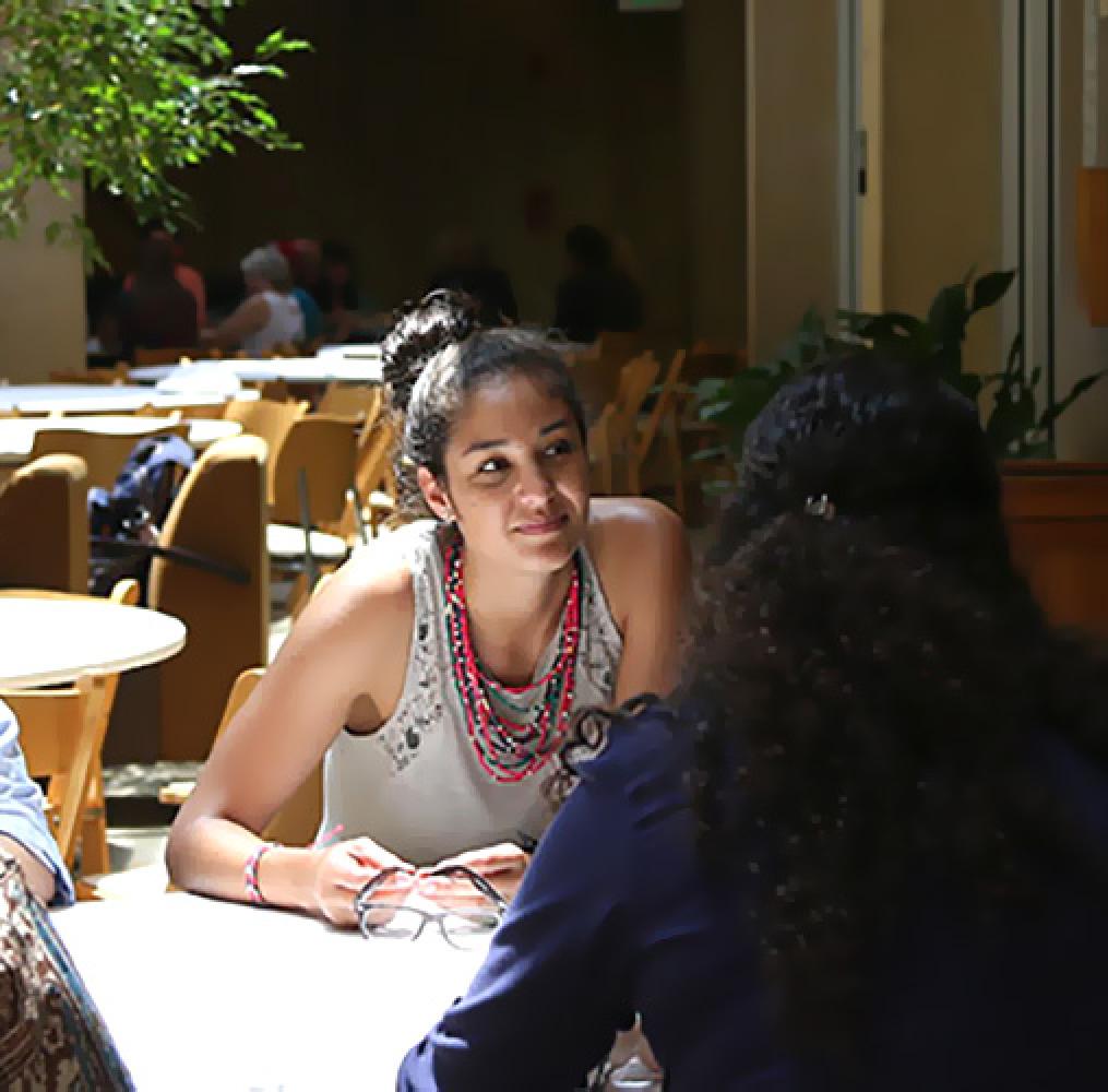 Two woman outdoors at a table having a discussion