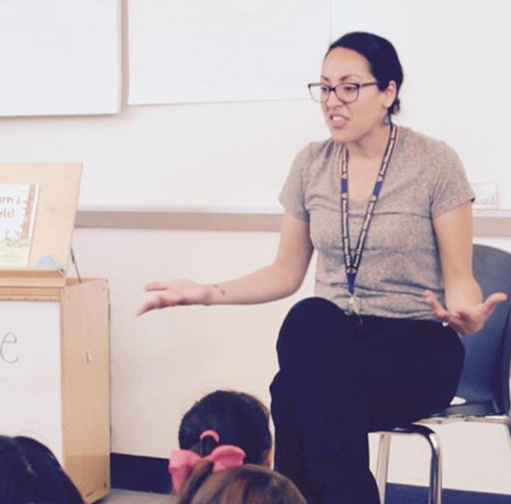 teacher seated in front of elementary aged students