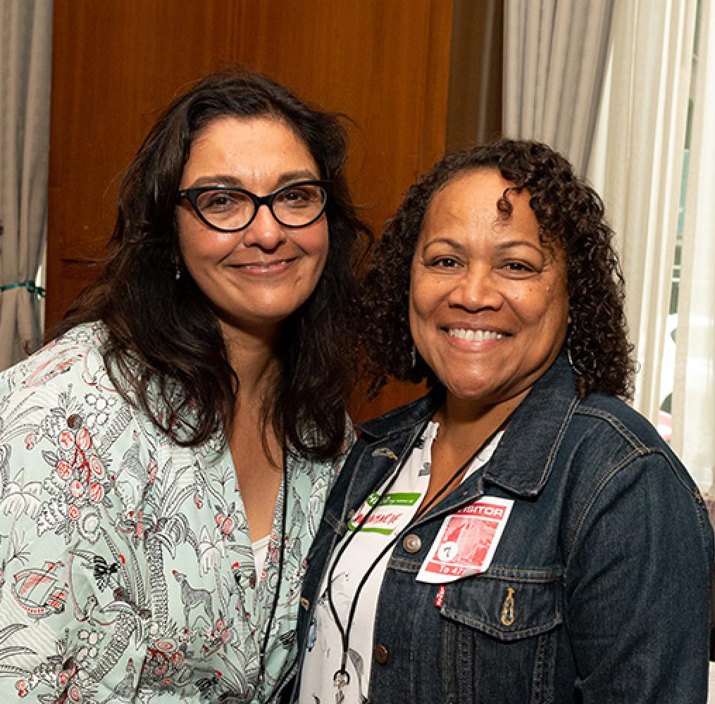 Two women smile in a conference setting