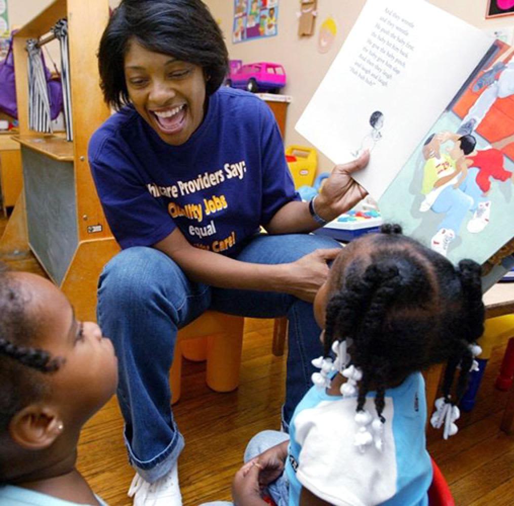 Female teacher reading a book to preschool-aged children