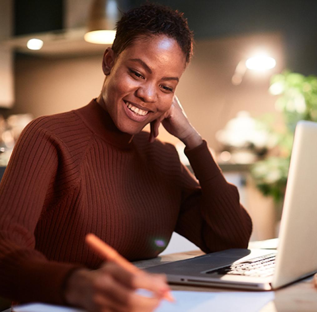 Woman writing in front of a laptop.