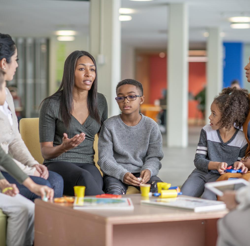 Parents and children seated in a circle having a serious discussion.