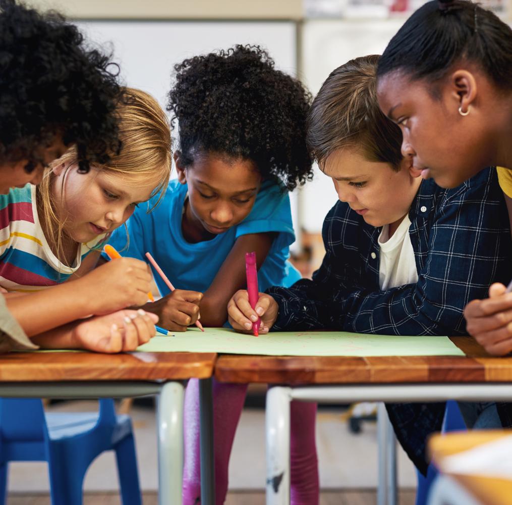 Group of middle school students working on a project at a school desk.