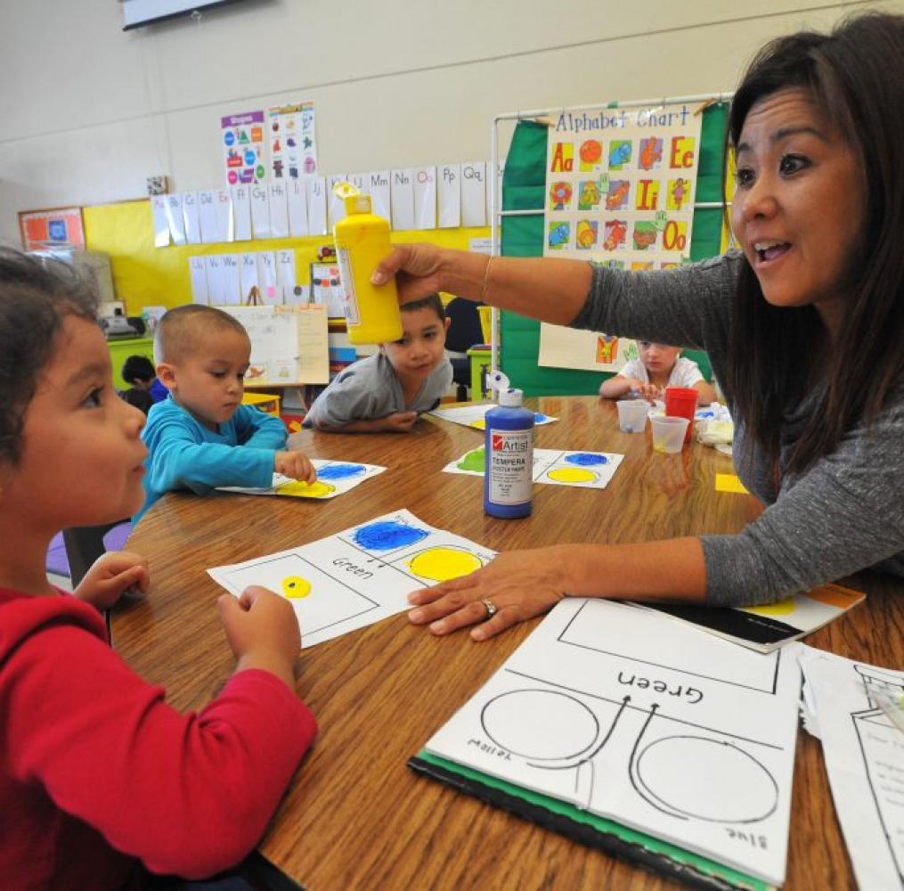 Elementary teacher interacting with students in a classroom.