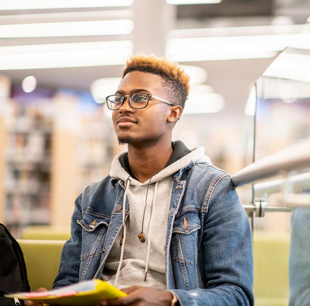 Young adult seated in a library.