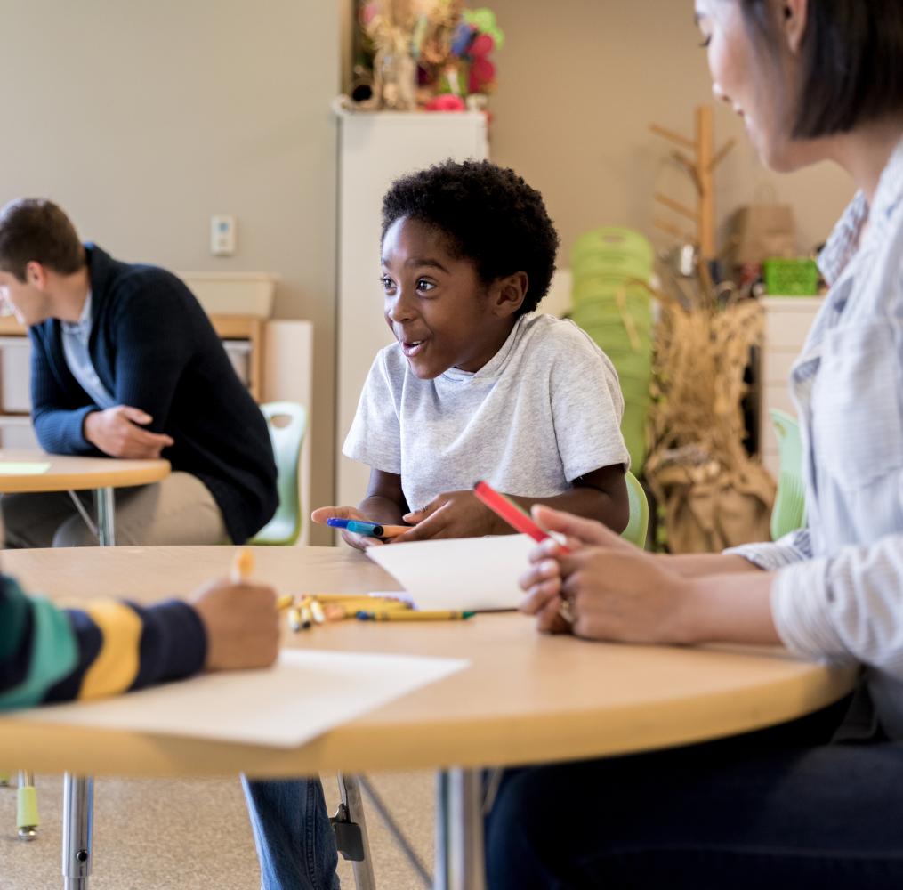 Smiling elementary student interacting with teachers and students. 