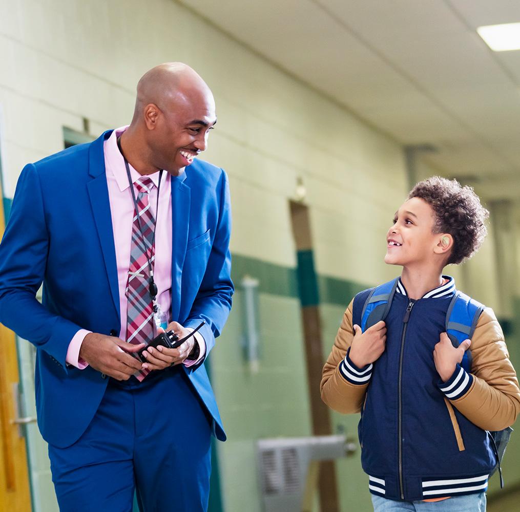 Teacher and elementary student talking in a school hallway.