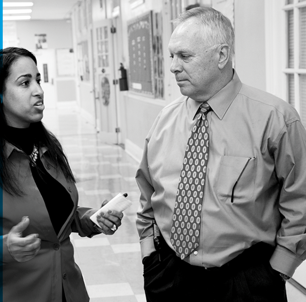 Teacher and student talking in a school hallway.