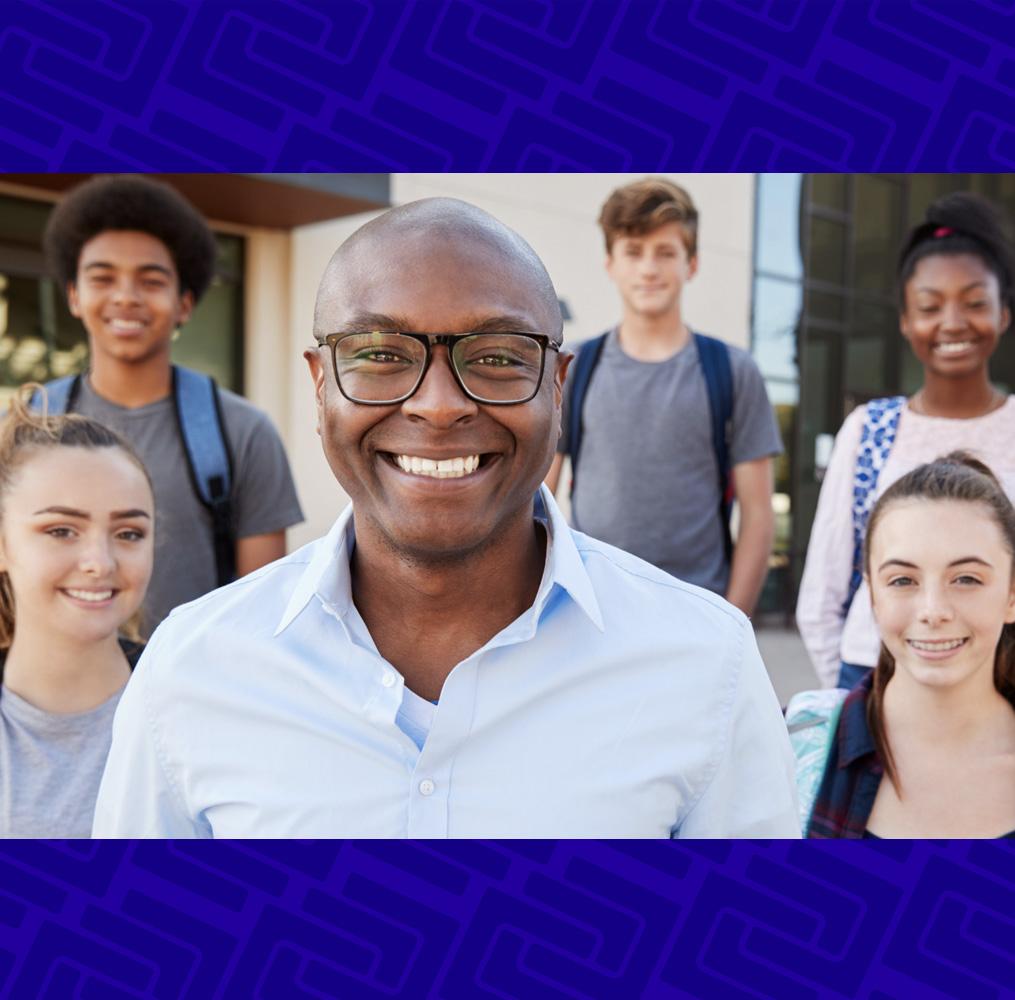 A teacher and students smiling at the camera.