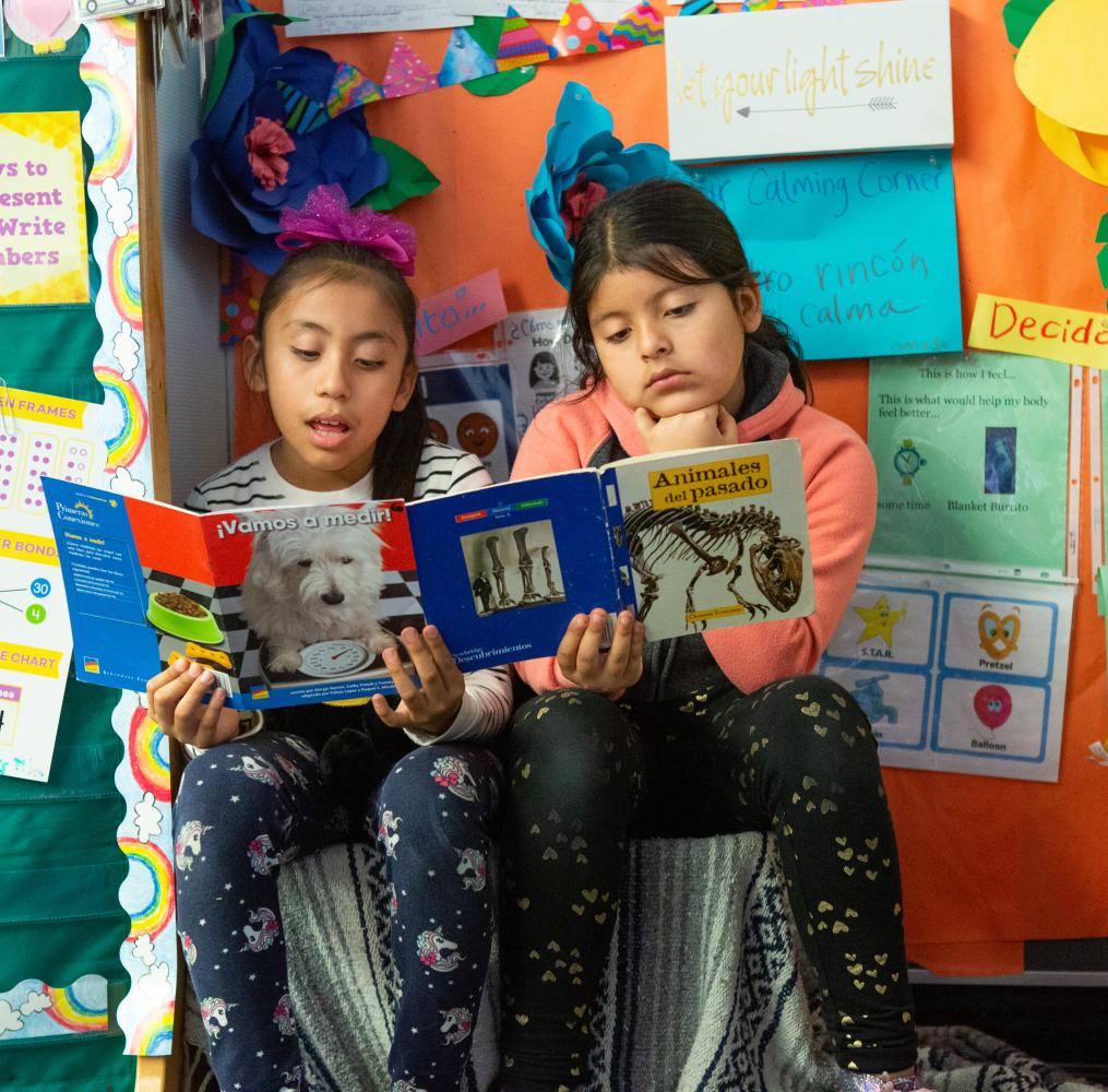 Two elementary students reading Spanish language books together.