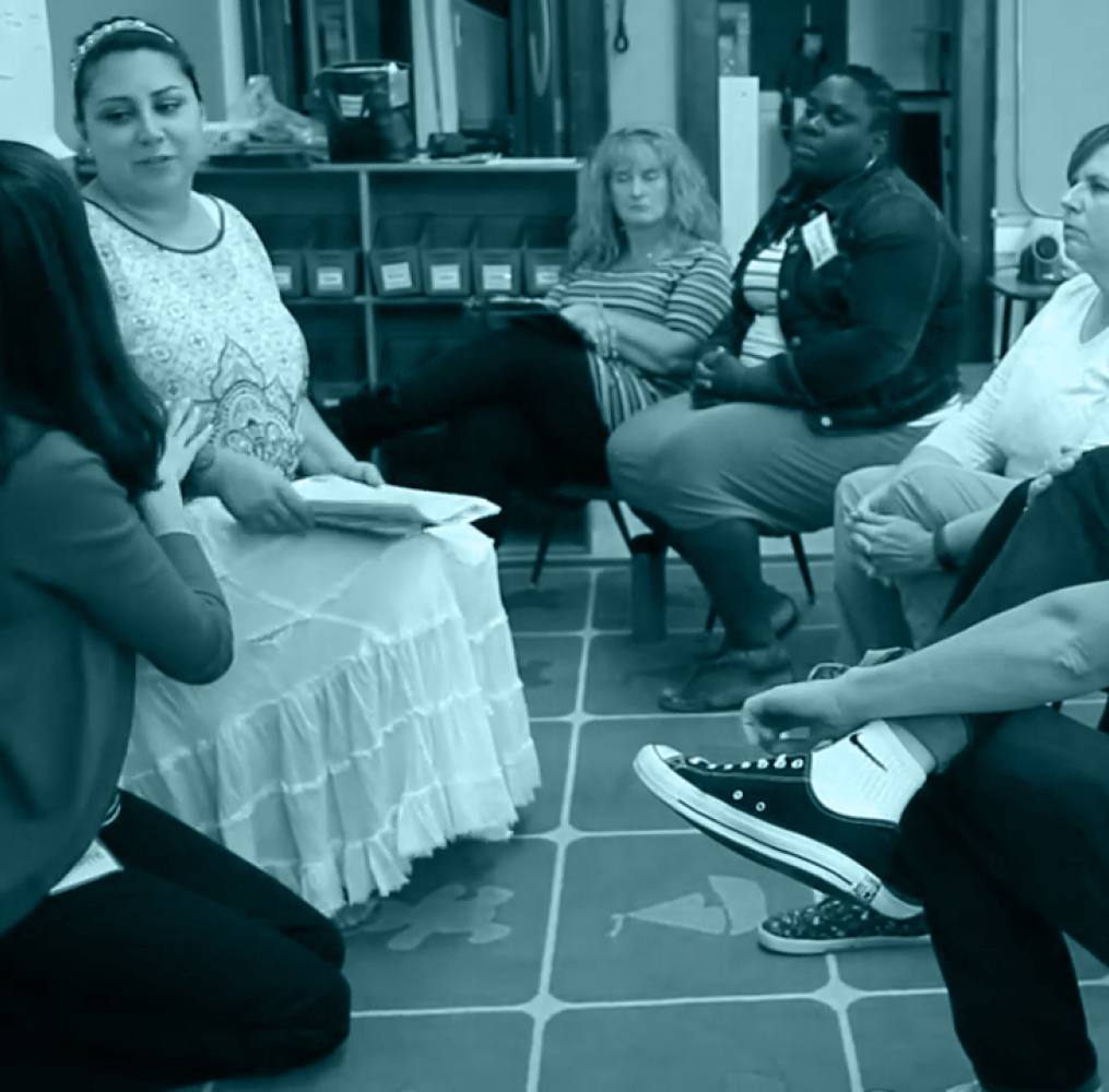 A group of adults seated in a circle having a discussion.