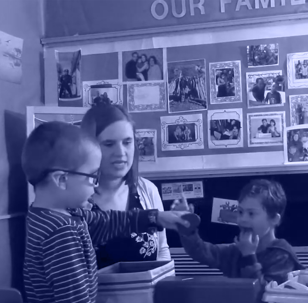 Preschool teacher helping students with an activity.