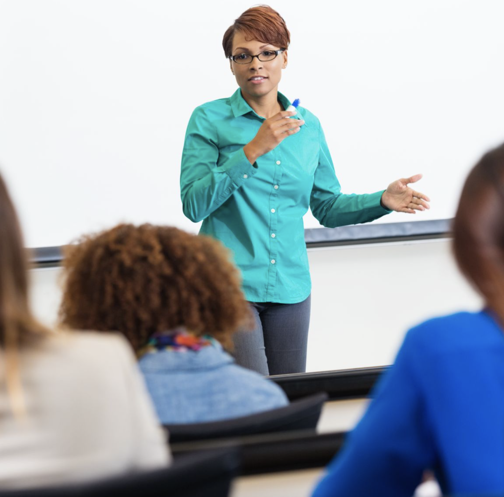 A woman presents in front of a classroom.