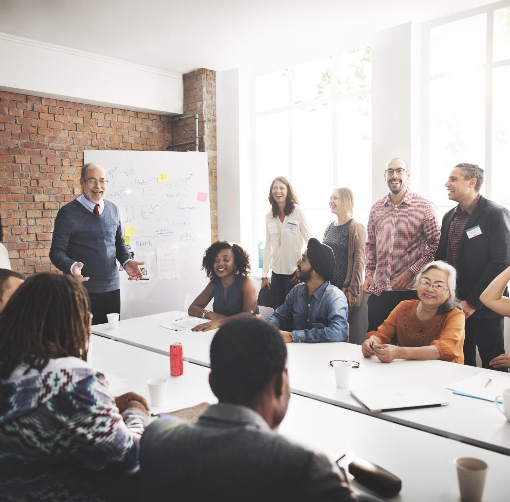 Group of adults listening to a presentation around a conference table.