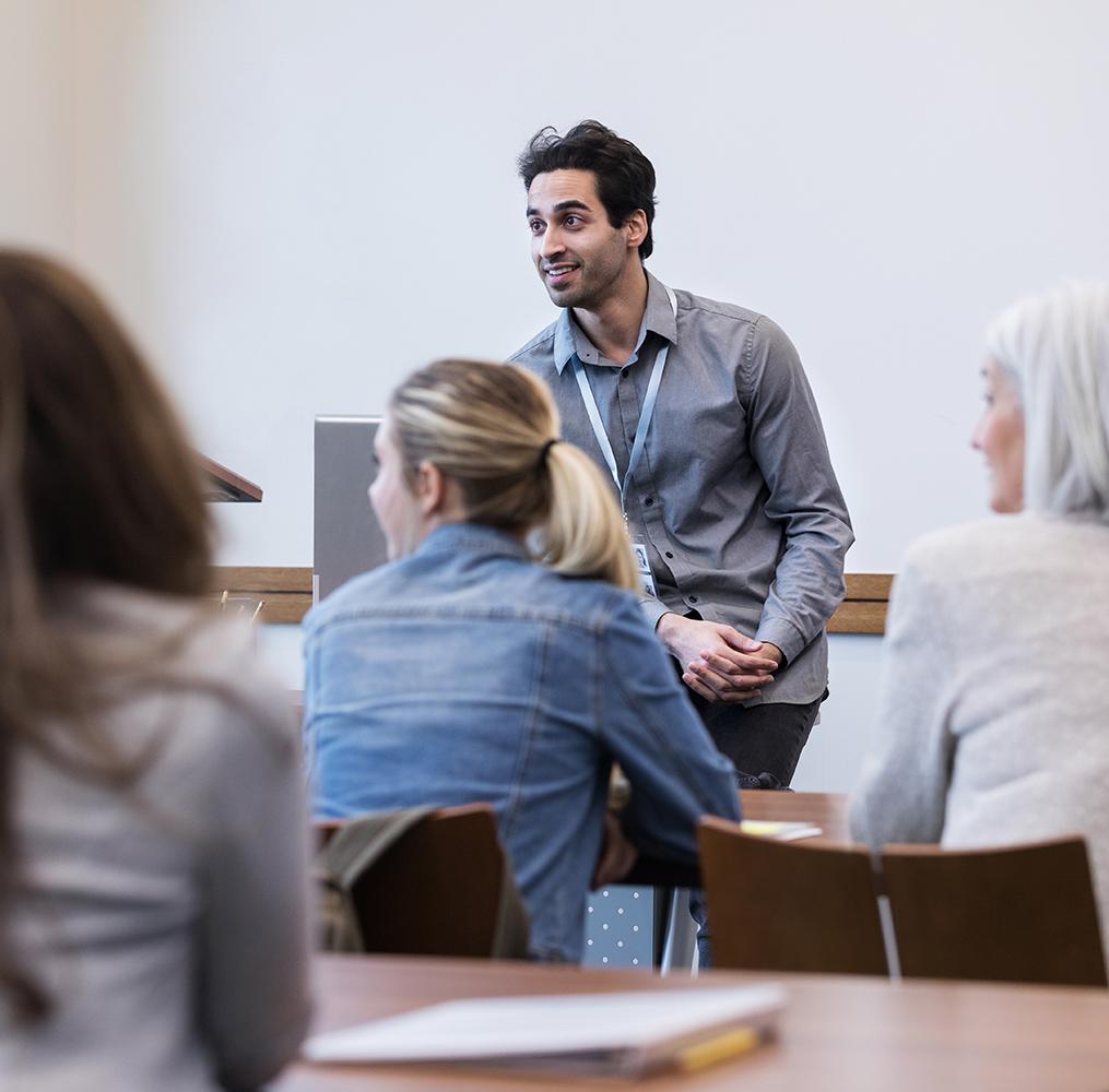 An educator speaking in front of a classroom with adults.