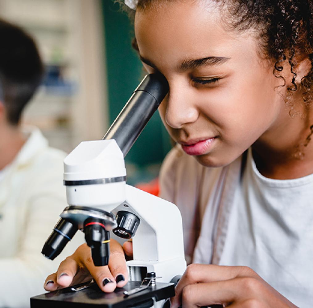 Middle school student looking through a microscope.