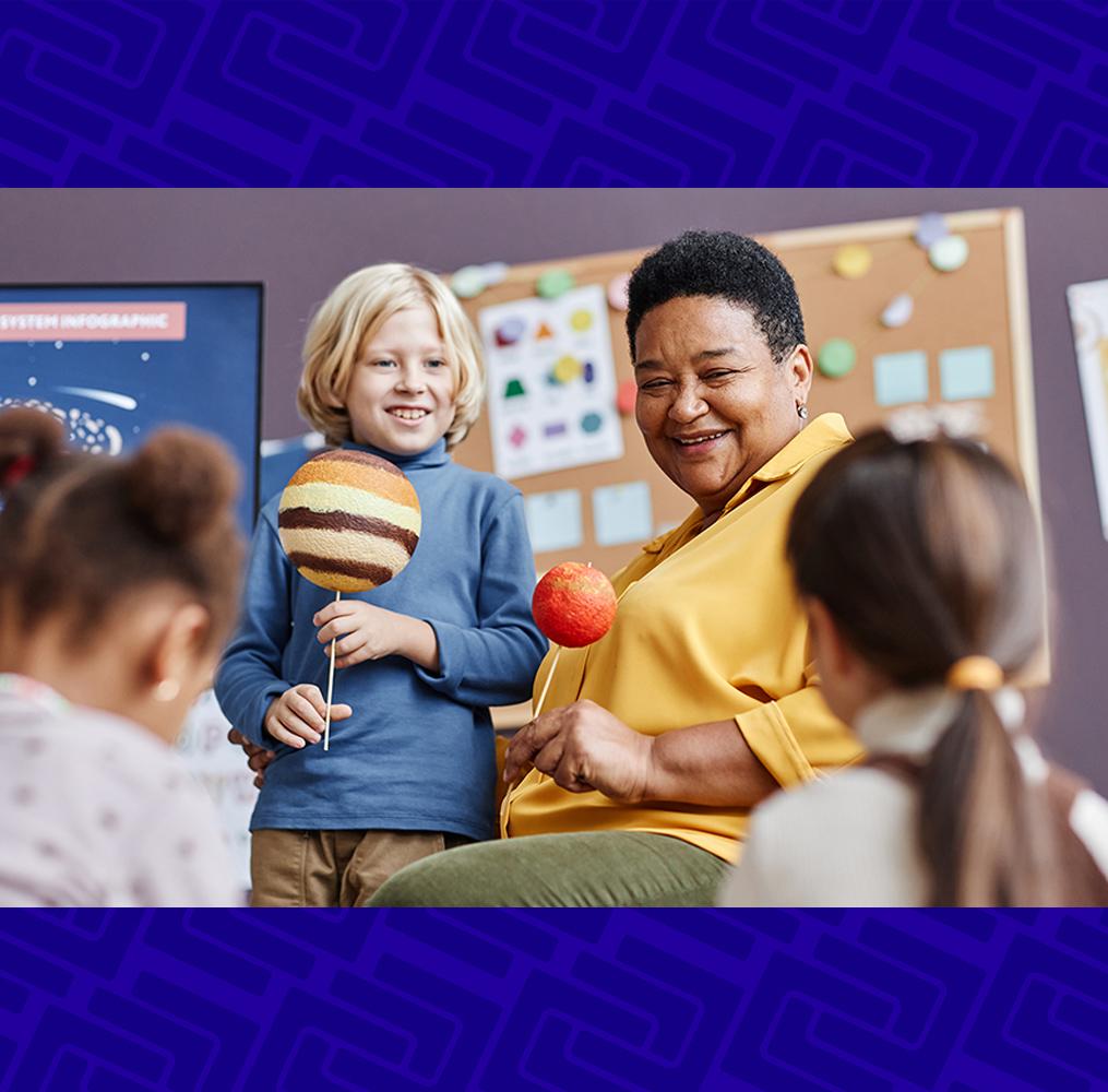 A teacher showing elementary students a planetary model.