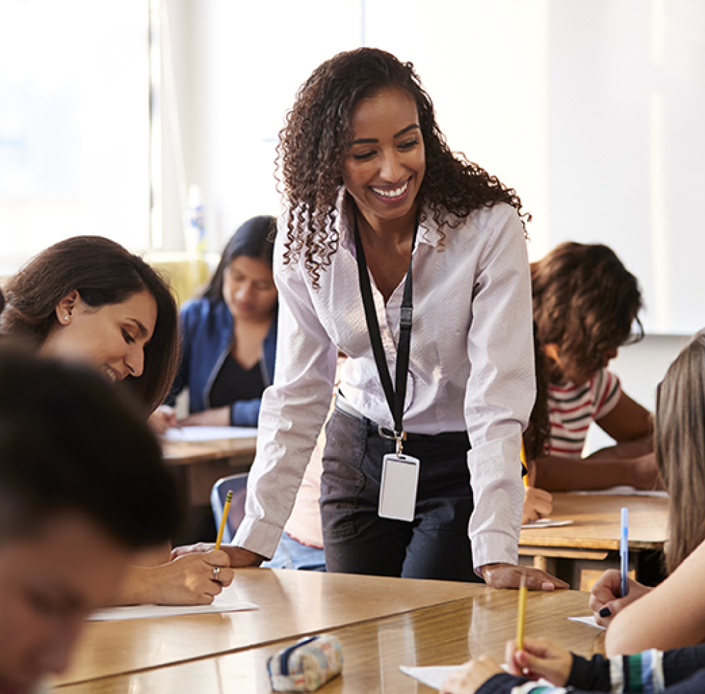 A teacher interacting with middle school students in a classroom.