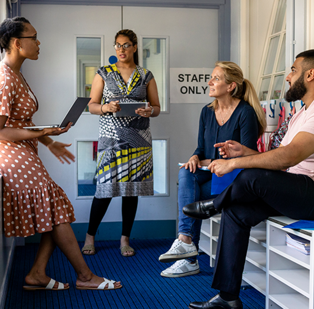 A group of teachers having a discussion in a school hallway.