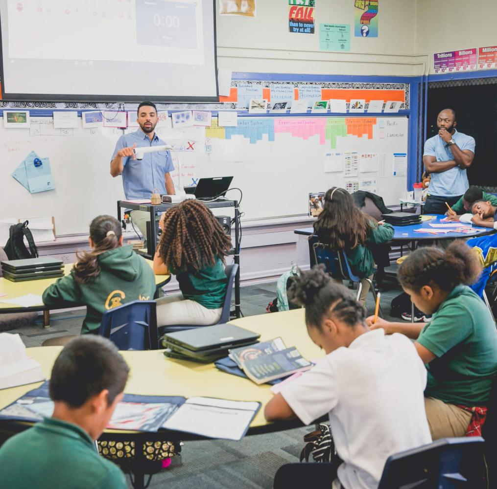 A teacher presenting a lesson while a student teacher watches.