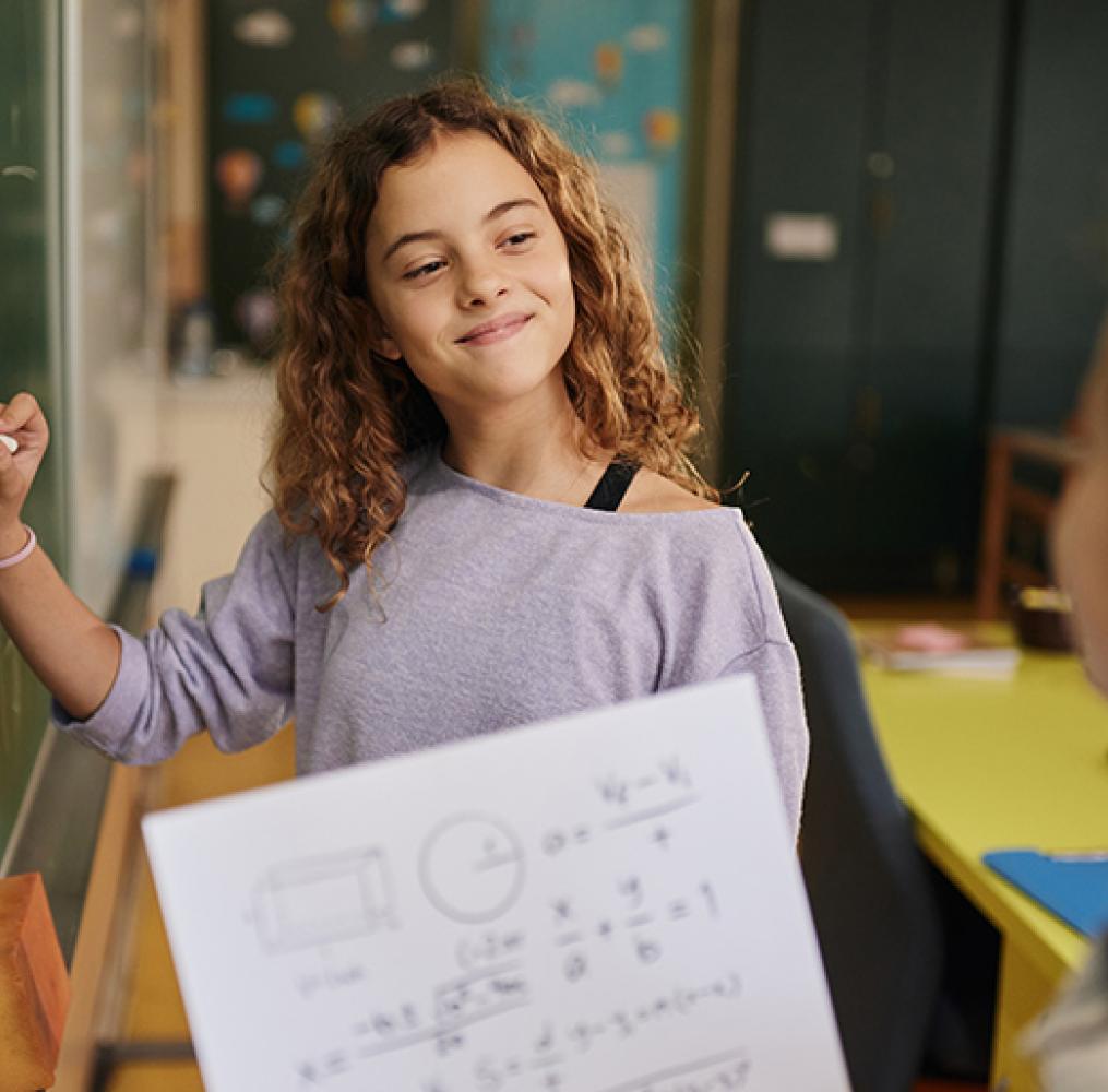 Two students working on a math equation on a blackboard.