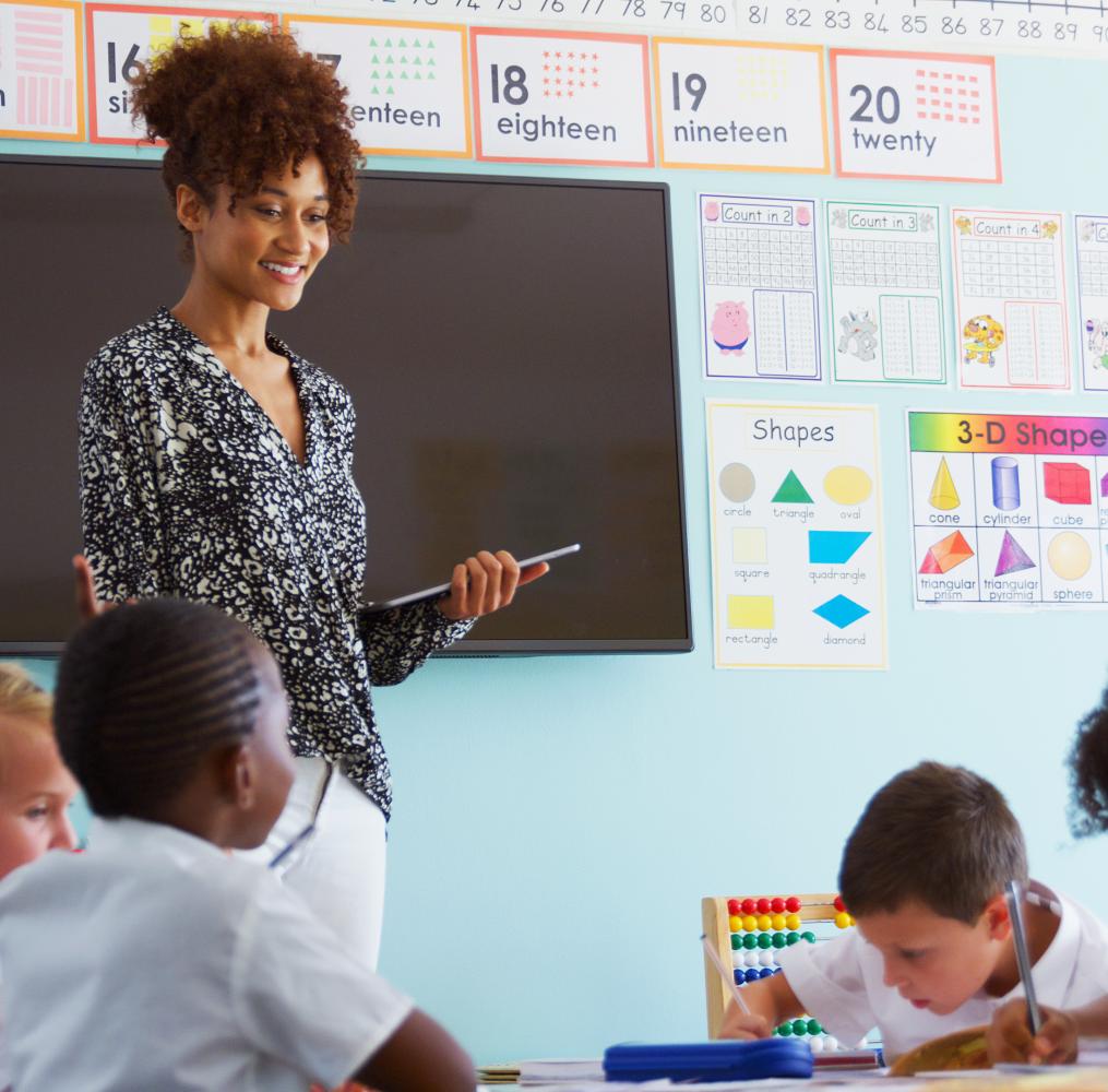 Teacher with digital tablet in from of a classroom.