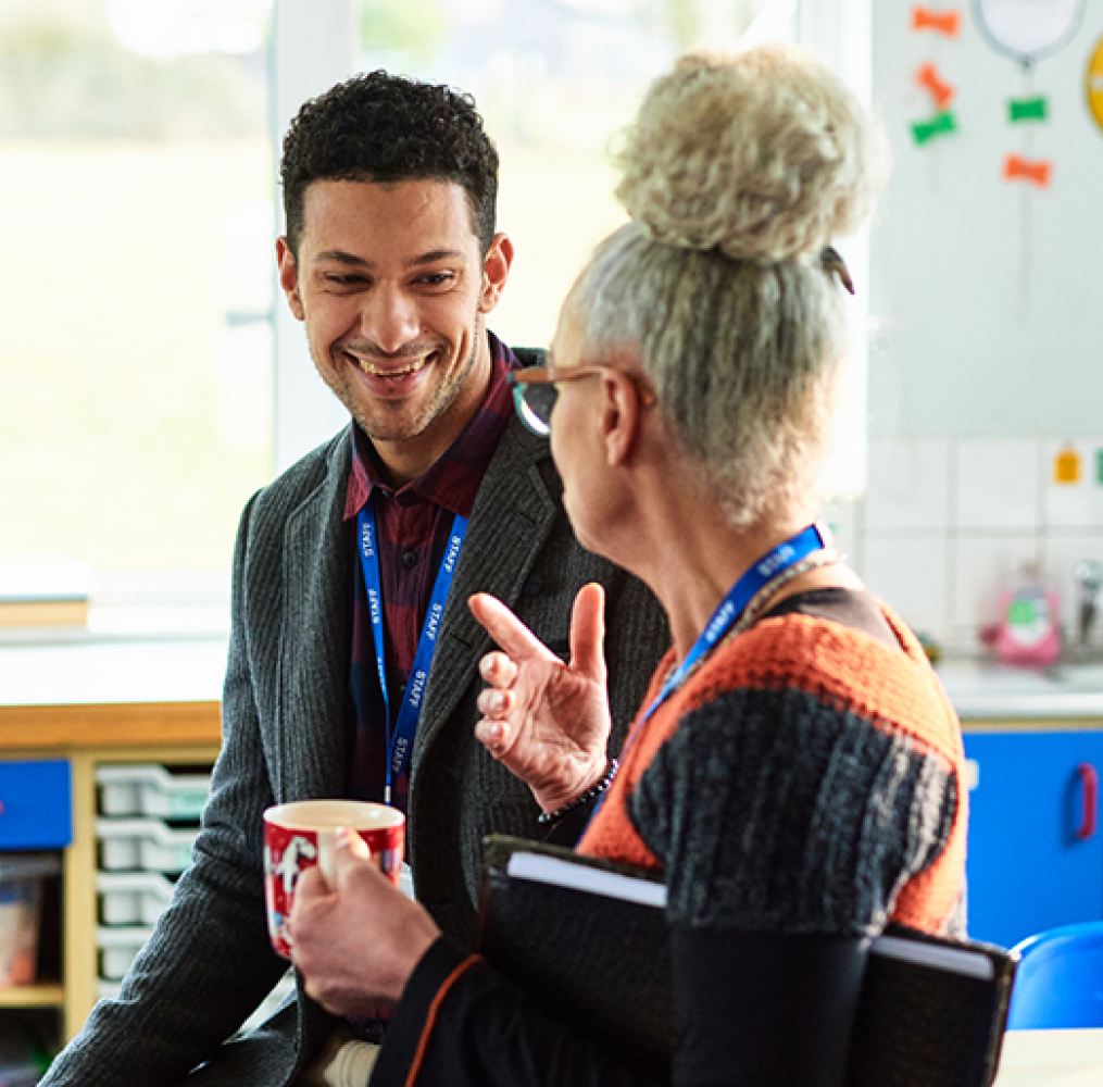 Two educators having a discussion in a classroom.