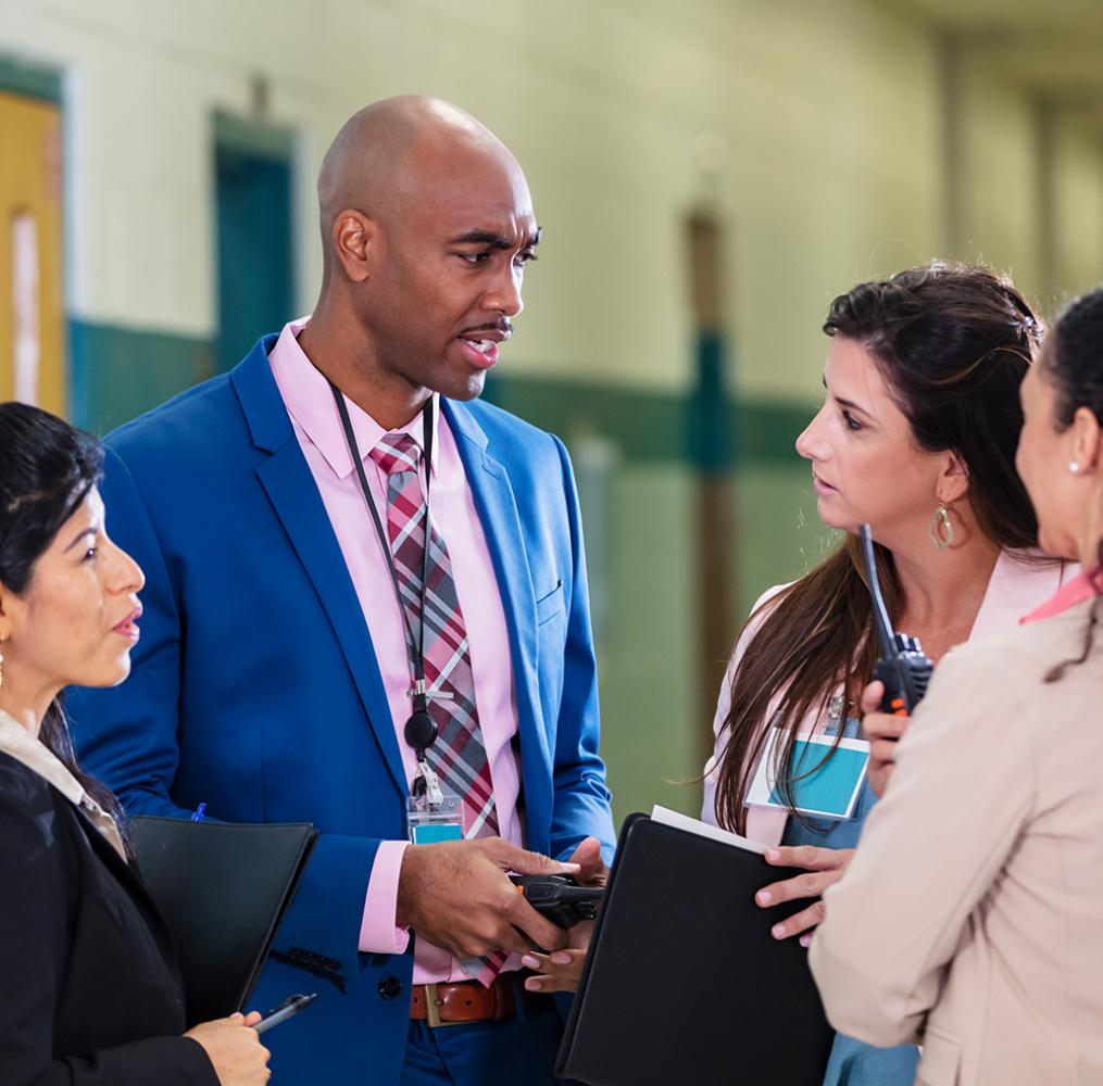 A group of teachers having a discussion in a school hallway.