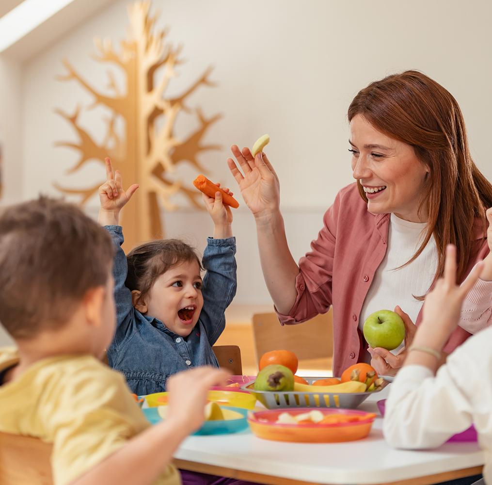 A teacher plays with elementary students at a table.