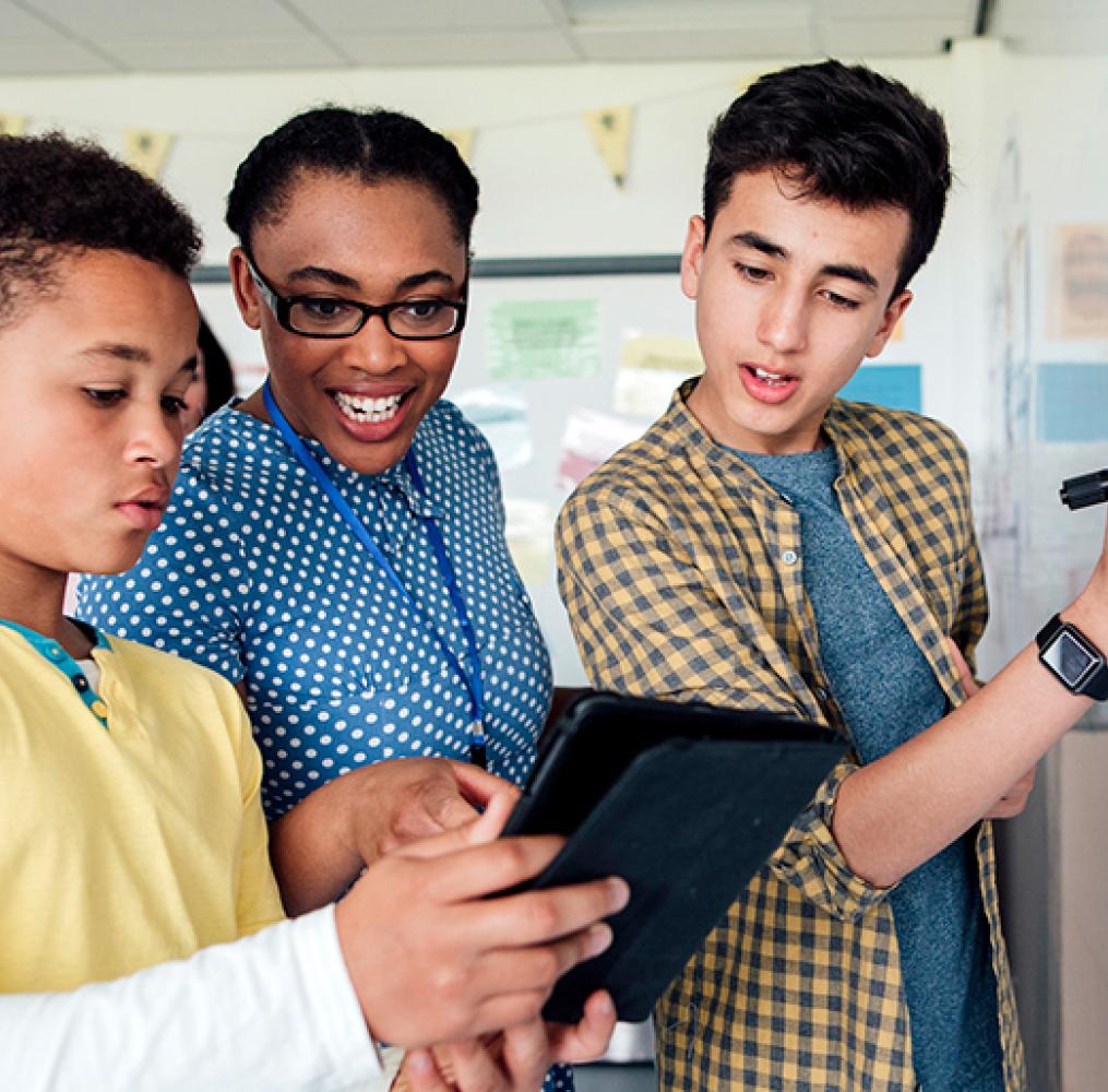 Three middle school students work on a math equation at a whiteboard.