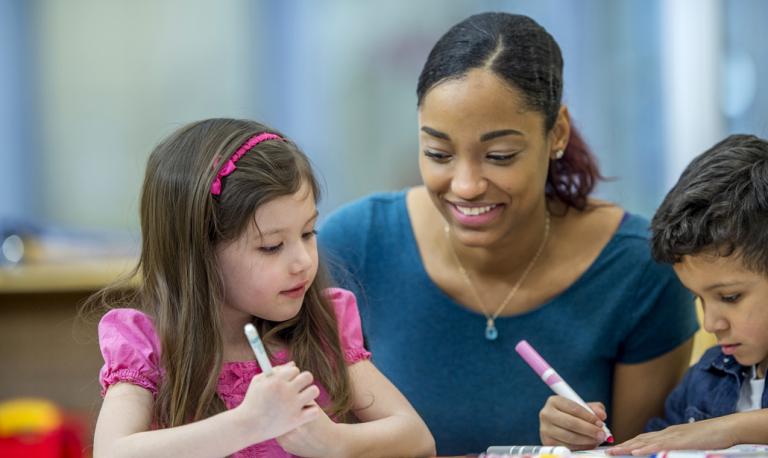 Teacher helping elementary students with an assignment.