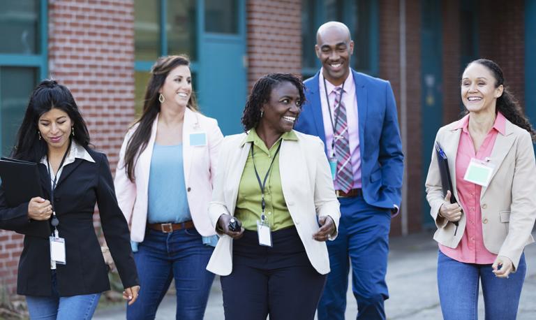 Group of teachers walking together outside a school.