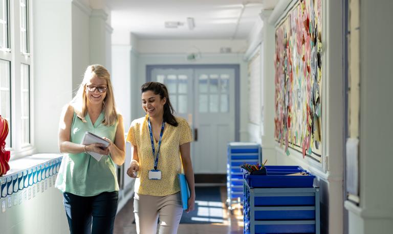 Two teachers talking in a school hallway.