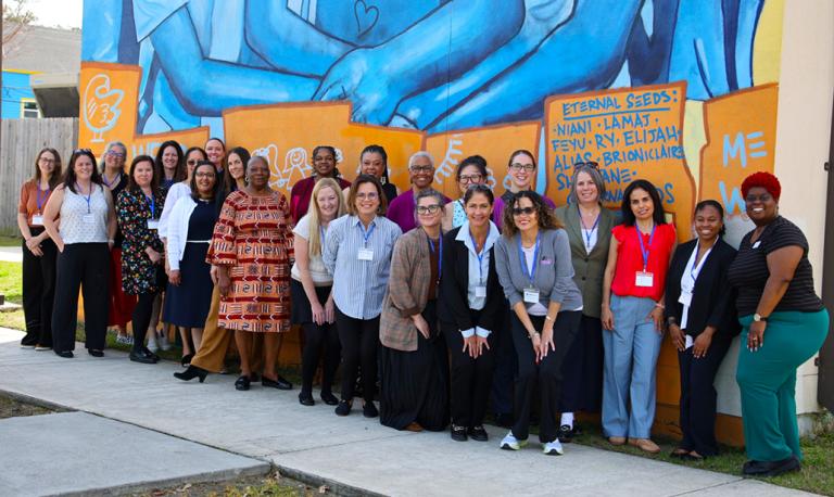 Group of educators in front of an outdoor mural.