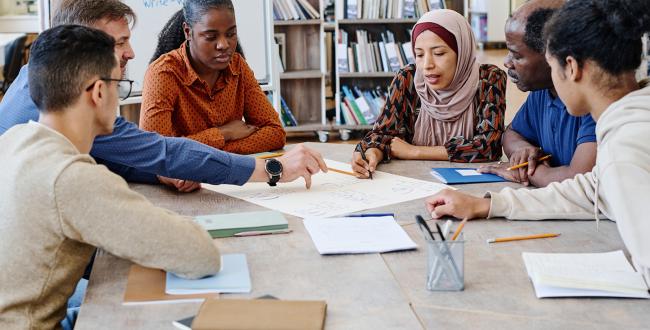 Group of adult students discussing an assignment.