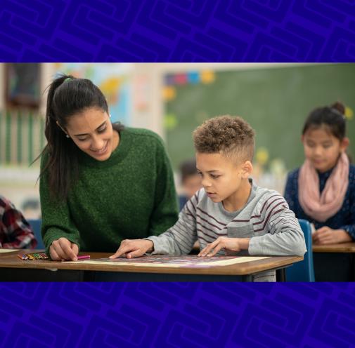A young teacher helping an elementary student with an assignment.