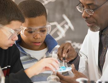 science teacher working on a project with two elementary aged students