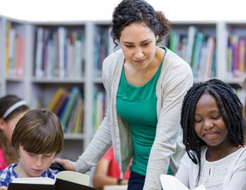 Teacher in classroom helping students at a table