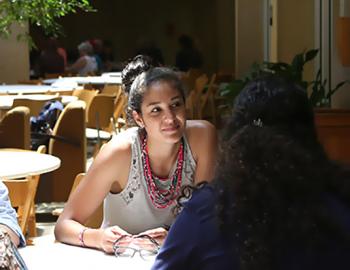 Two woman outdoors at a table having a discussion