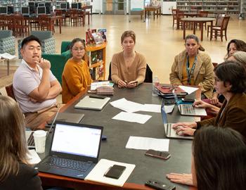 a group on people talking at a conference table in a library