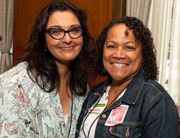 Two women smile in a conference setting