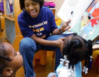 Female teacher reading a book to preschool-aged children
