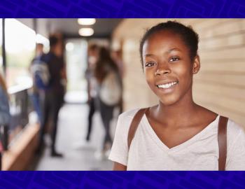 African American girl smiling with a backpack and classmates in the background.