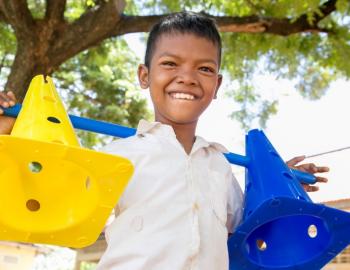 Young boy smiling while holding two safety cones