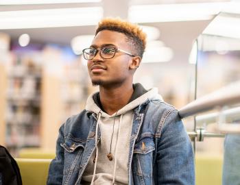 Young adult seated in a library.